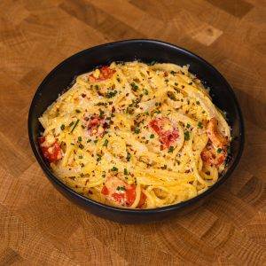 Creamy tomato spaghetti pasta in a black bowl.