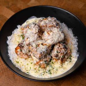 Creamy garlic parmesan chicken over rice in a black bowl.