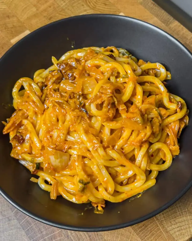 Crispy bacon and sesame oil added to the udon noodles and kimchi sauce. - GENIUS EATS Crispy bacon and sesame oil added to the udon noodles and kimchi sauce.