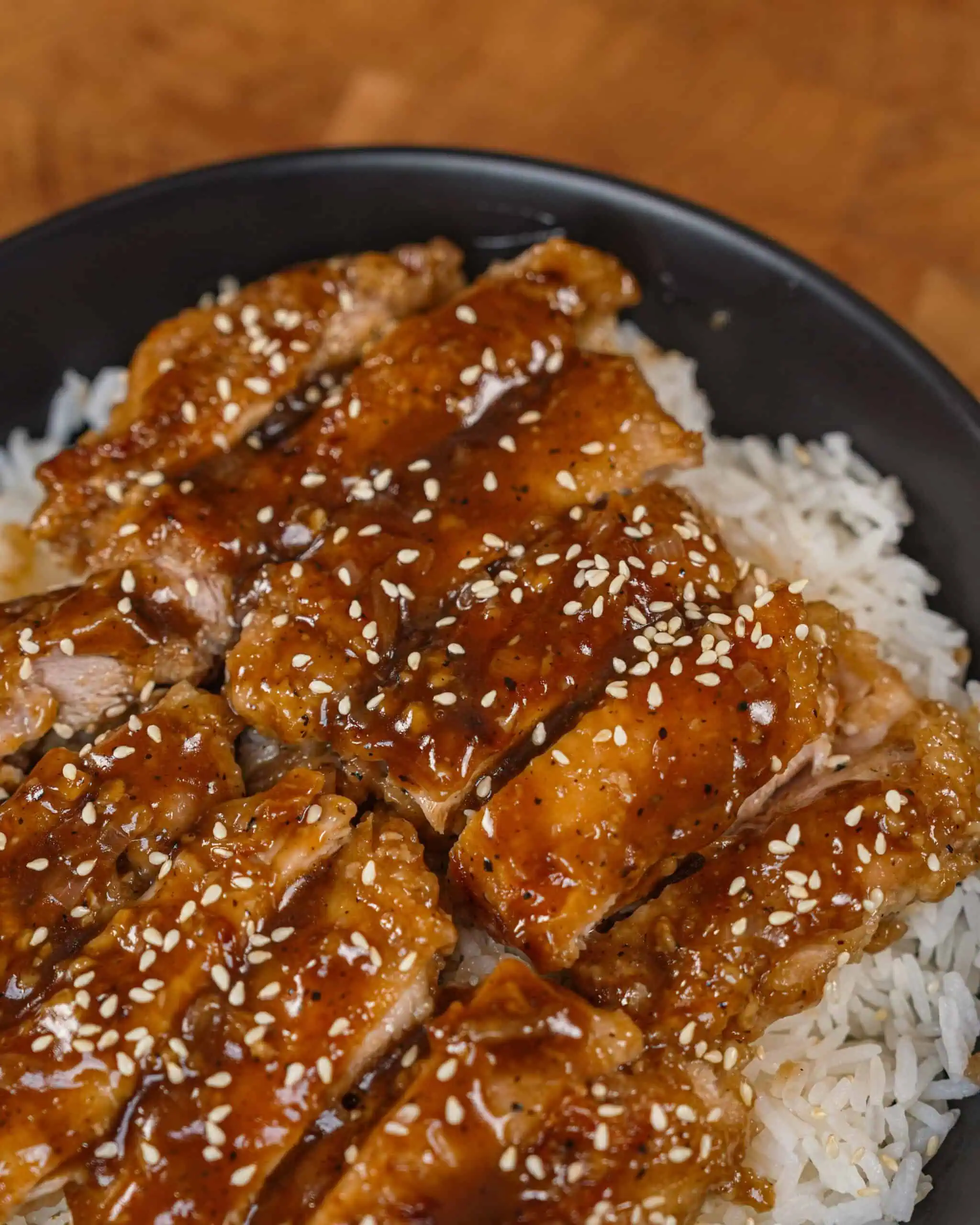 Glazed sesame chicken slices served over steamed rice in a bowl. - GENIUS EATS Crispy Black Pepper Chicken