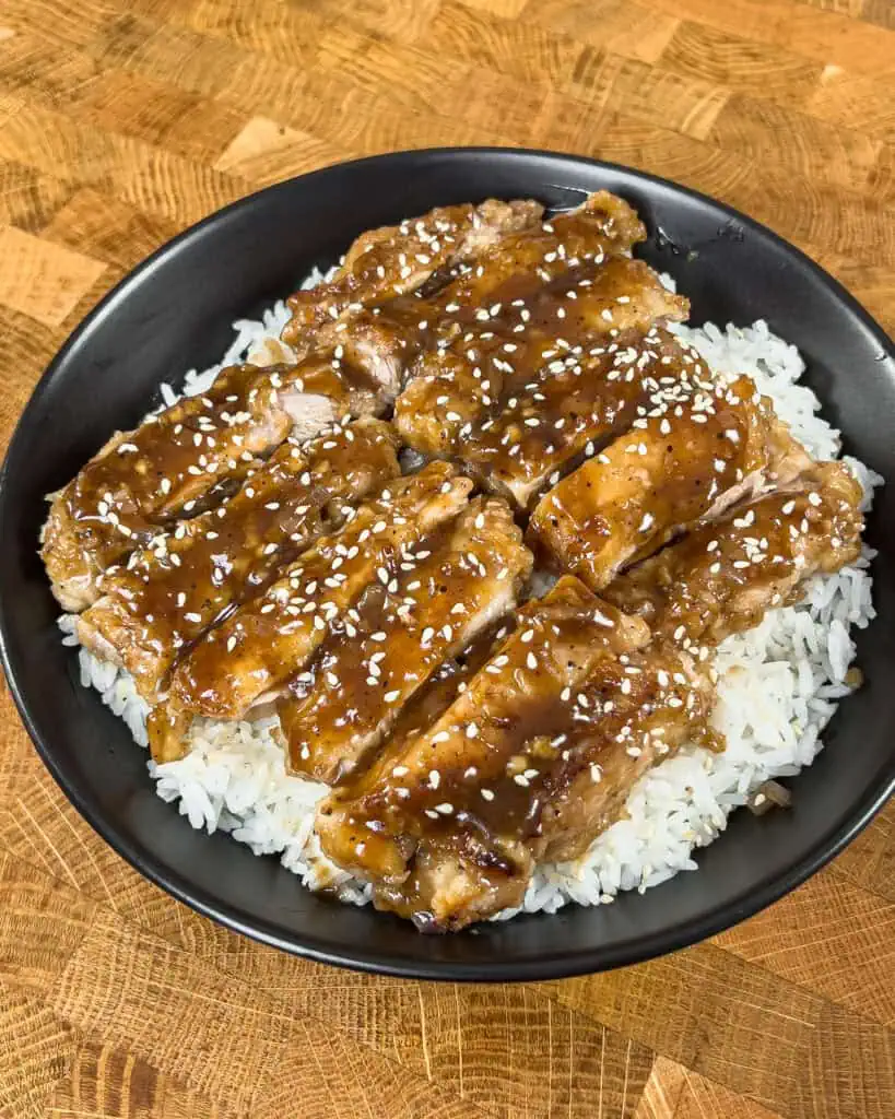 Slices of crispy black pepper chicken served over steamed rice sprinkled with sesame seeds - GENIUS EATS Slices of crispy black pepper chicken served over steamed rice sprinkled with sesame seeds