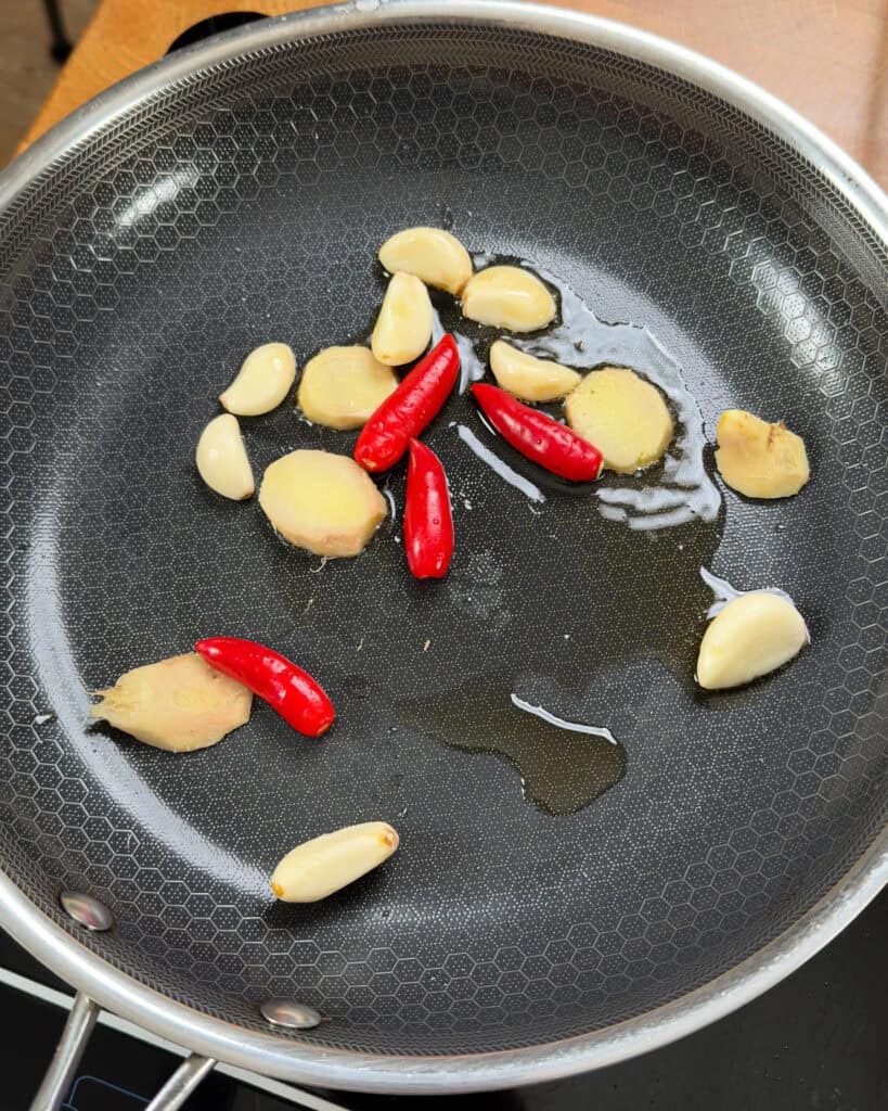 Aromatics of garlic ginger and red chili frying in sesame oil in a wok