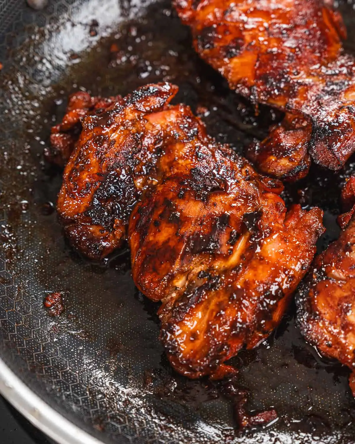 Charred glazed chicken thighs searing in a pan - GENIUS EATS Asian style sticky chicken
