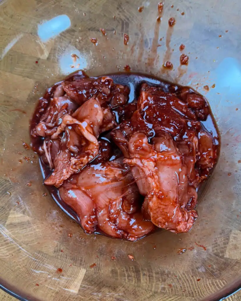 Chicken pieces coated in dark red honey-garlic marinade soaking for flavor before cooking - GENIUS EATS Chicken pieces coated in dark red honey-garlic marinade soaking for flavor before cooking