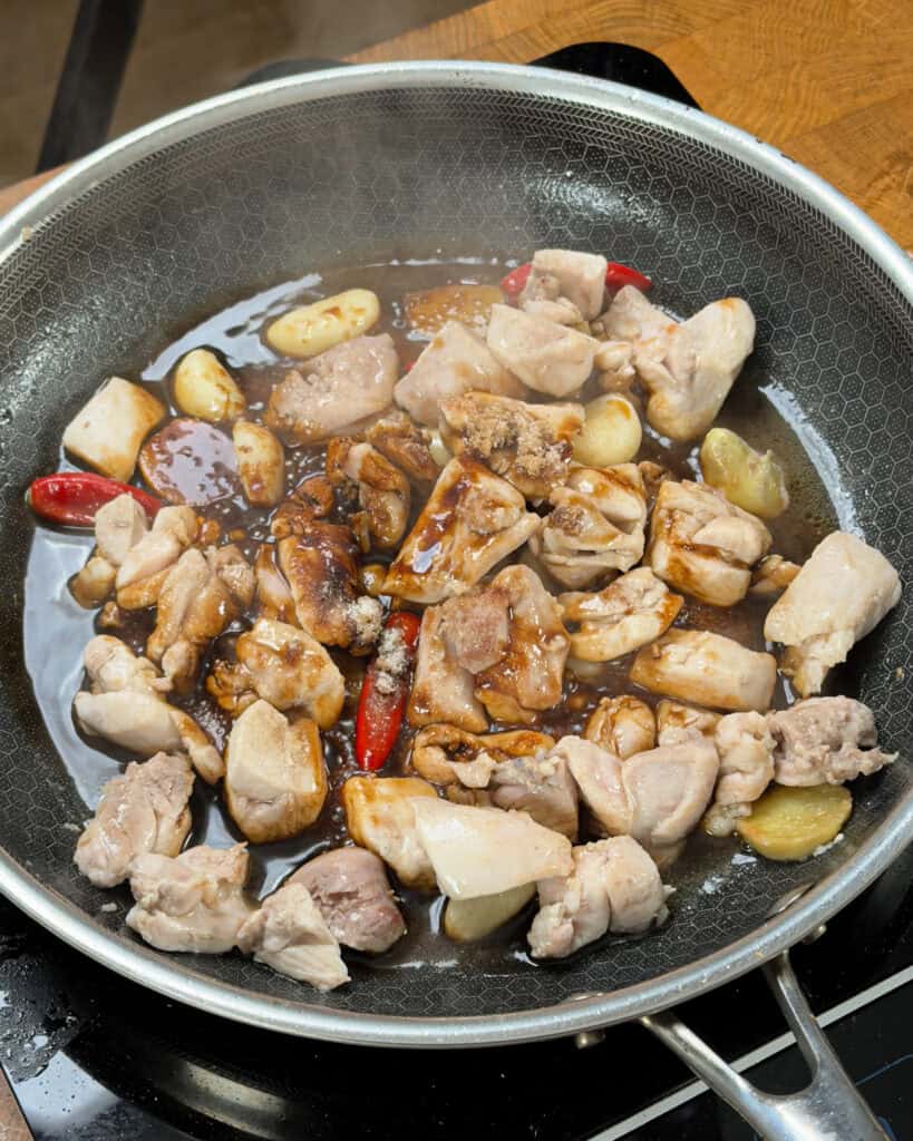 Chicken simmering in soy-based sauce for Three Cup Chicken