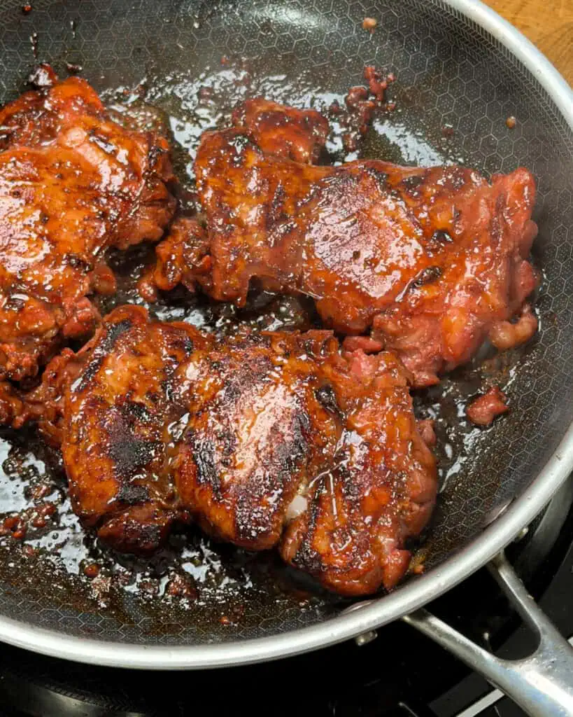 Glazed chicken thighs coated in rich sauce ready to serve from the pan - GENIUS EATS Glazed chicken thighs coated in rich sauce ready to serve from the pan
