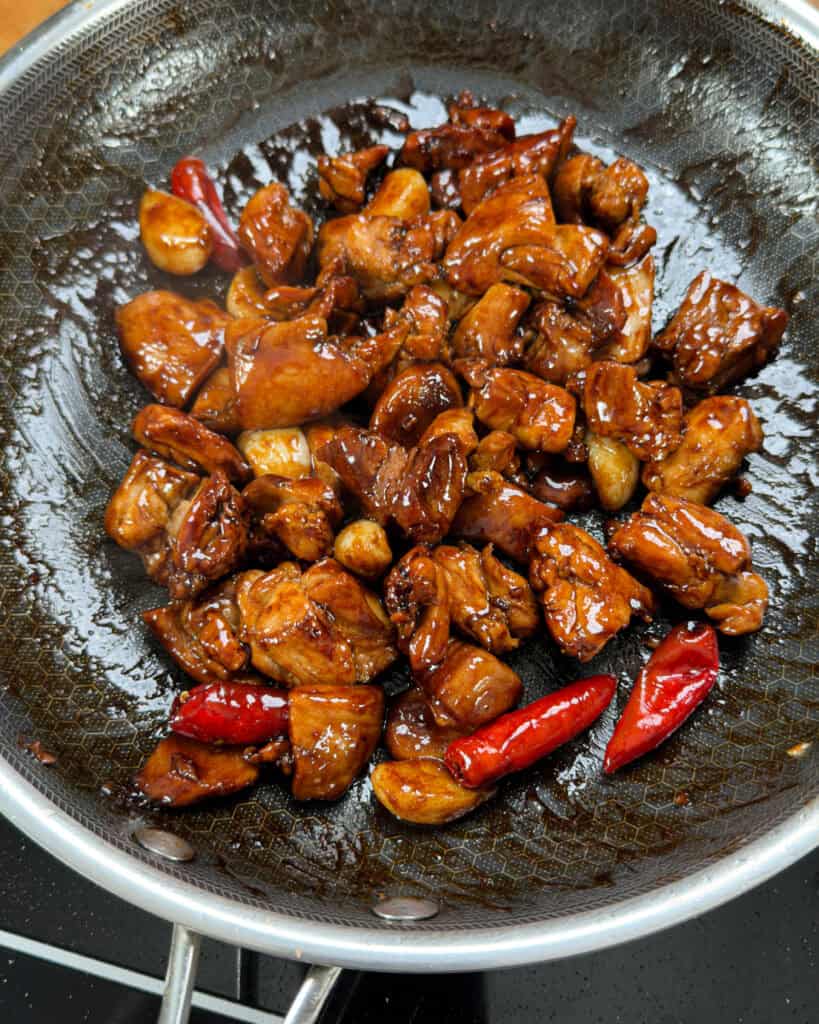 Glossy brown chicken coated in reduced soy sauce glaze in a wok