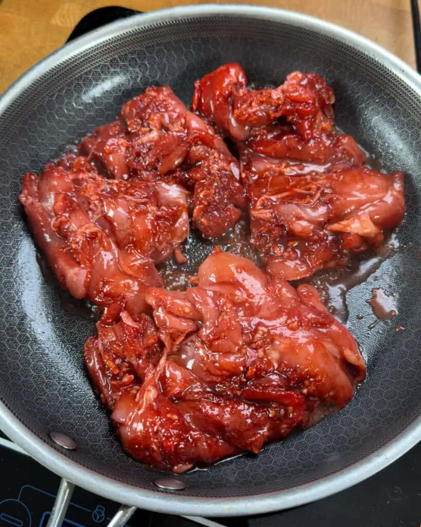 Marinated chicken added to a hot pan starting to sear and sizzle - GENIUS EATS Marinated chicken added to a hot pan starting to sear and sizzle