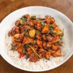 Basil garlic chicken stir-fry served over fluffy white rice in a bowl.