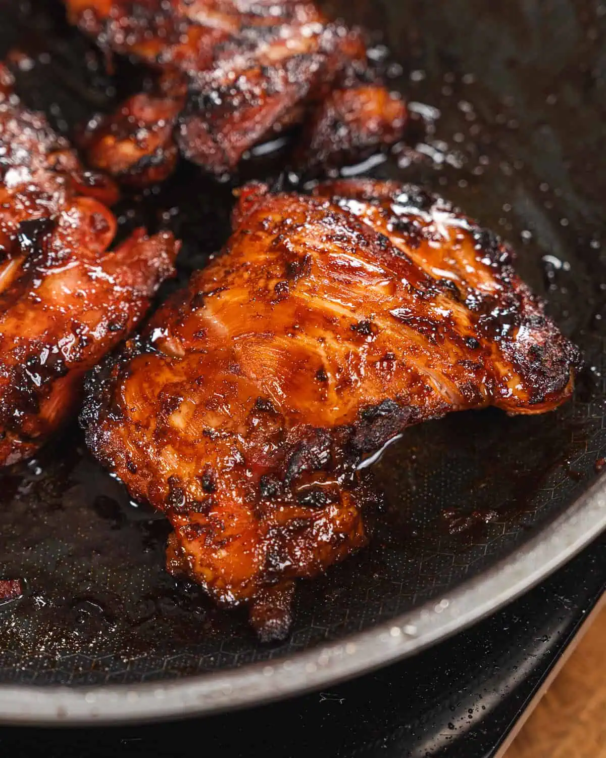 Glazed grilled chicken thigh in a sizzling pan - GENIUS EATS five spice chicken