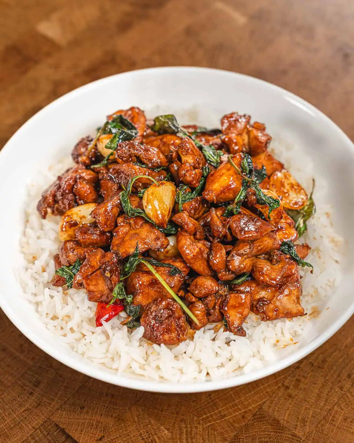 Basil garlic chicken stir-fry served over fluffy white rice in a bowl. - GENIUS EATS three cup chicken