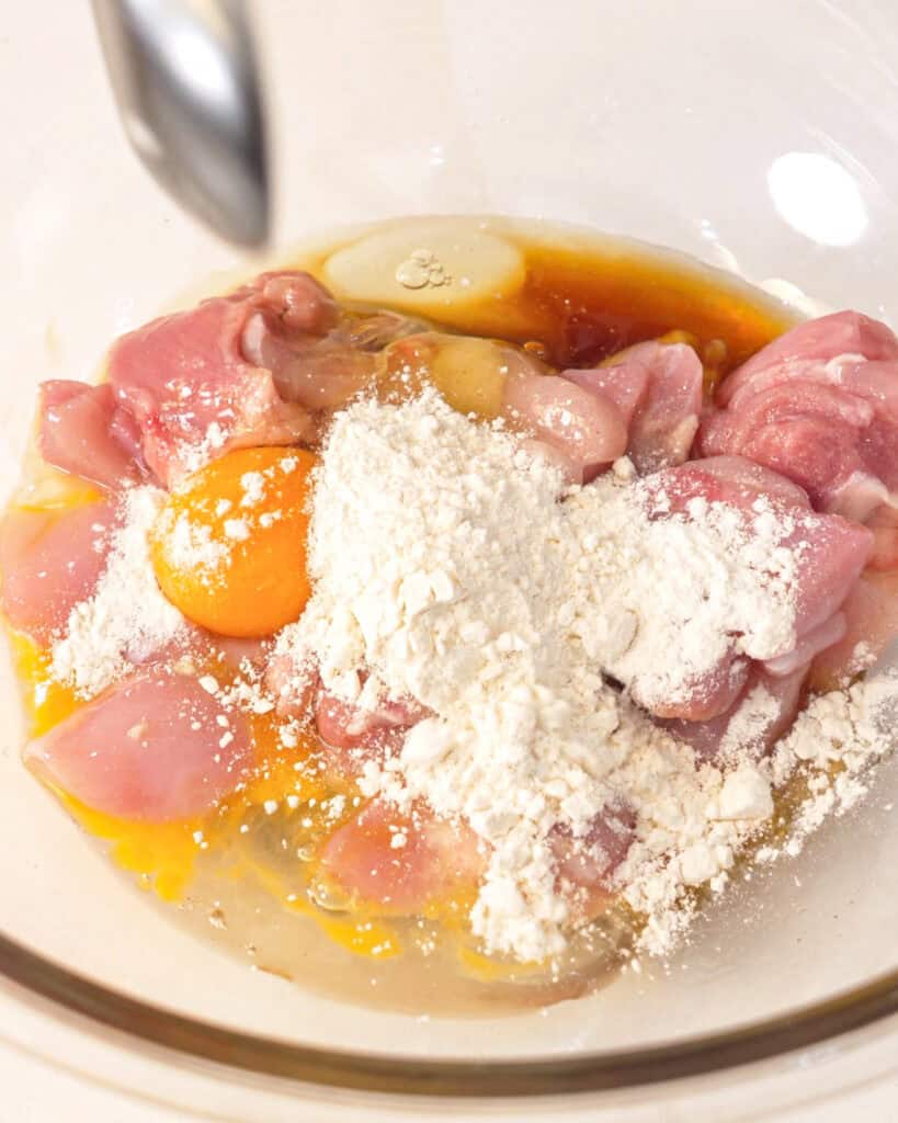 Adding soy sauce, egg, and flour to chicken for karaage marinade - GENIUS EATS Adding soy sauce, egg, and flour to chicken for karaage marinade