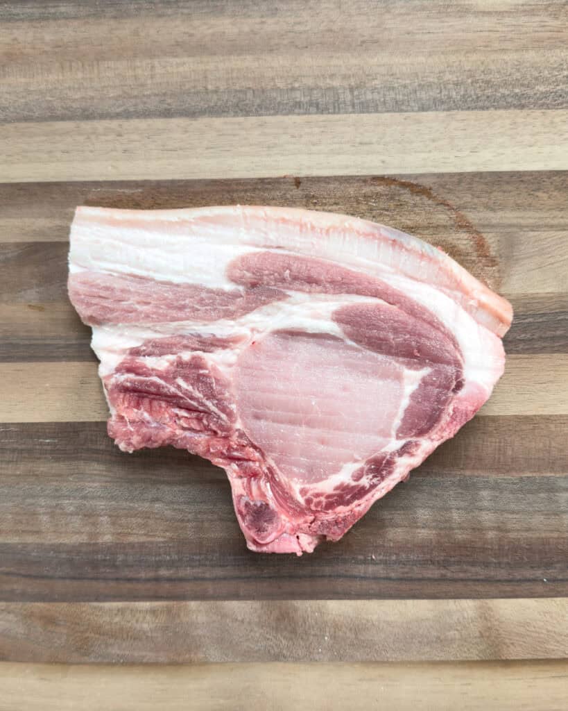 Raw pork chop prepared for Vietnamese lemongrass pork chops on wooden cutting board