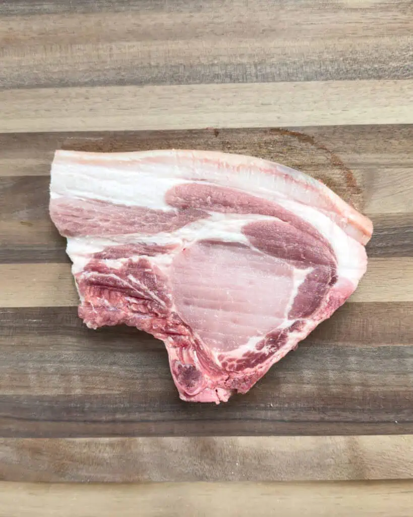 Raw pork chop prepared for Vietnamese lemongrass pork chops on wooden cutting board - GENIUS EATS Raw pork chop prepared for Vietnamese lemongrass pork chops on wooden cutting board