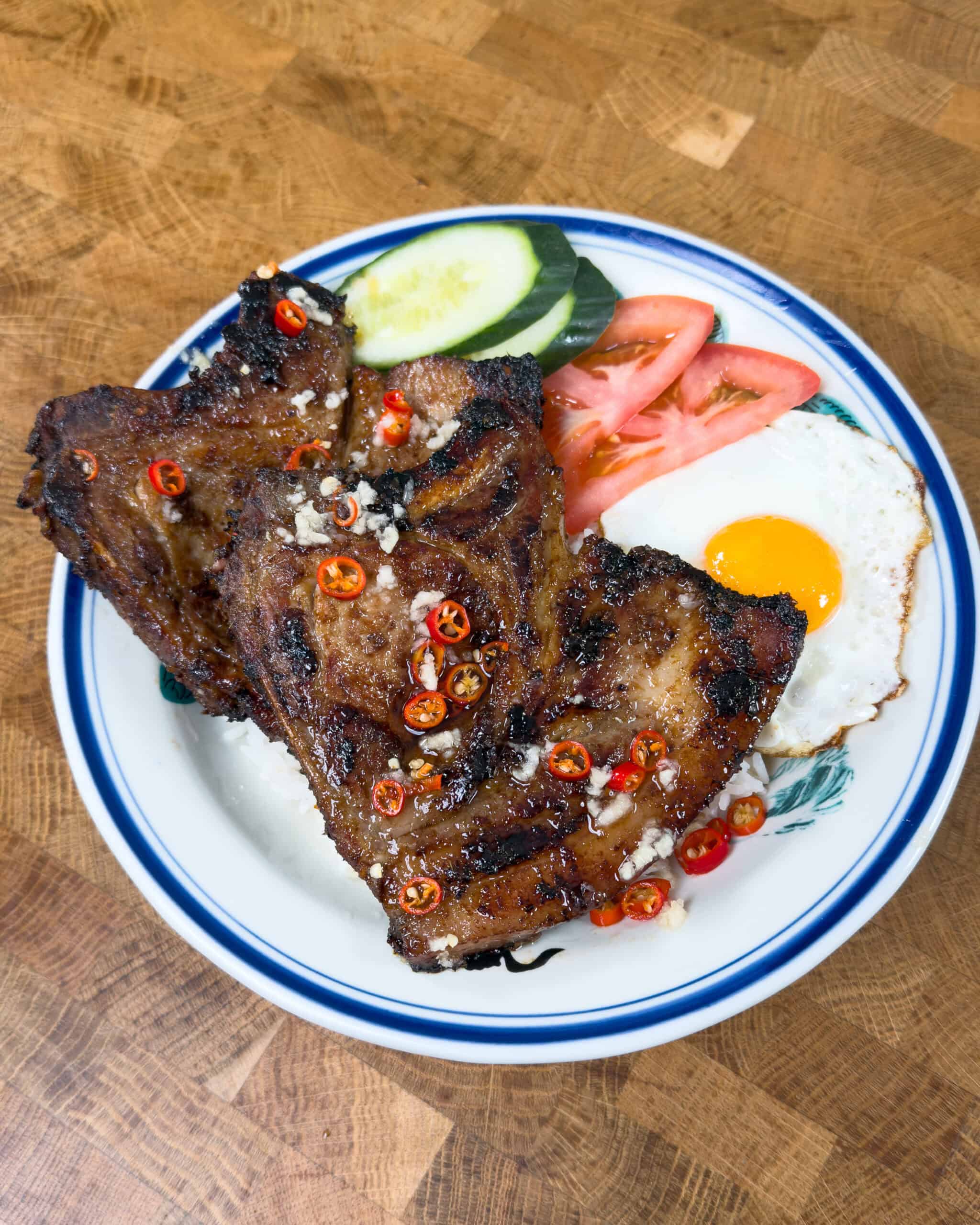 Vietnamese lemongrass pork chops served with fried egg cucumber and tomato