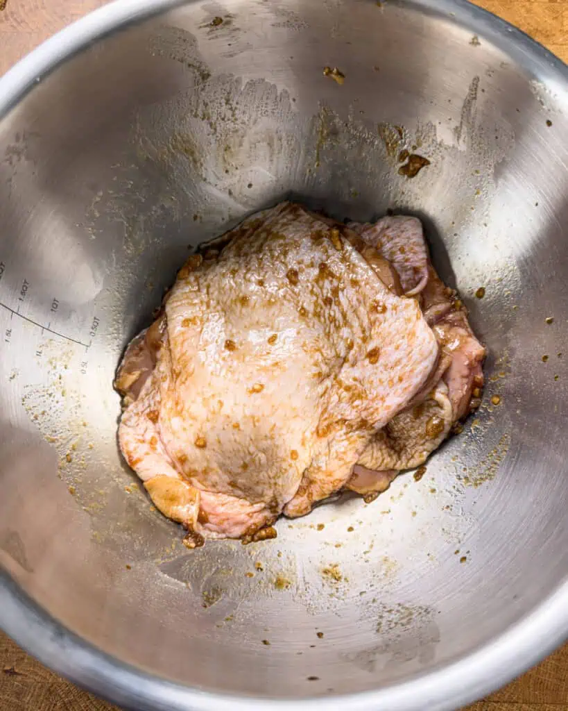 Chicken thighs being marinated with soy sauce and aromatics - GENIUS EATS Chicken thighs being marinated with soy sauce and aromatics