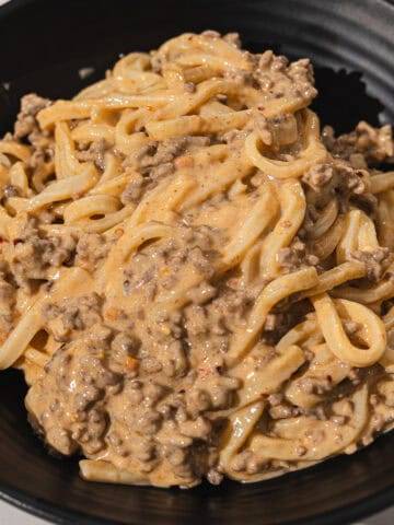Creamy beef stroganoff with noodles in a black bowl, delicious comfort food.
