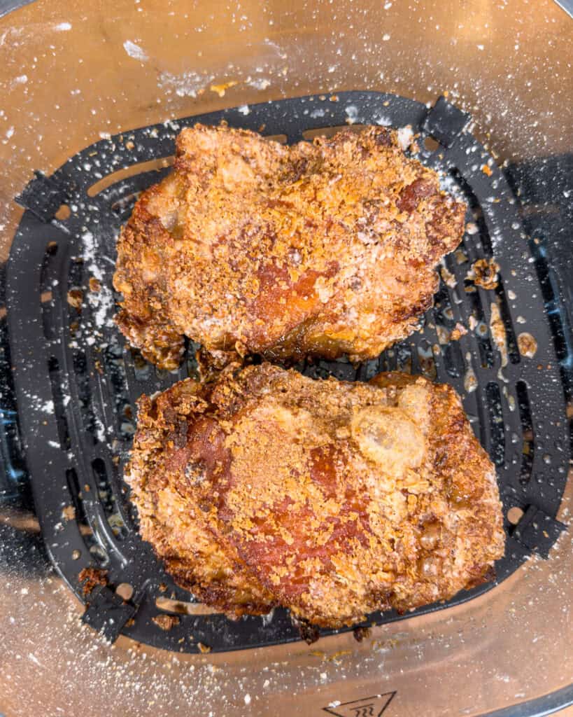 Crispy air fryer chicken thighs cooking until golden brown