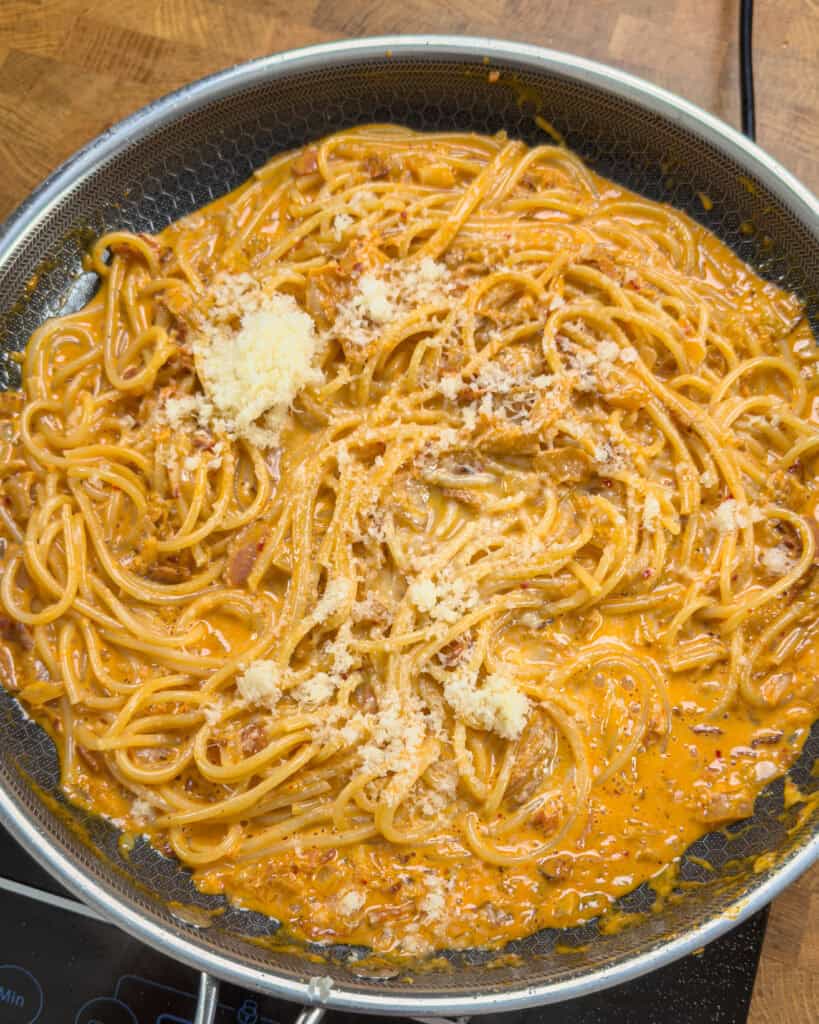 Grated Parmesan scattered over Kimchi Bacon Pasta in pan