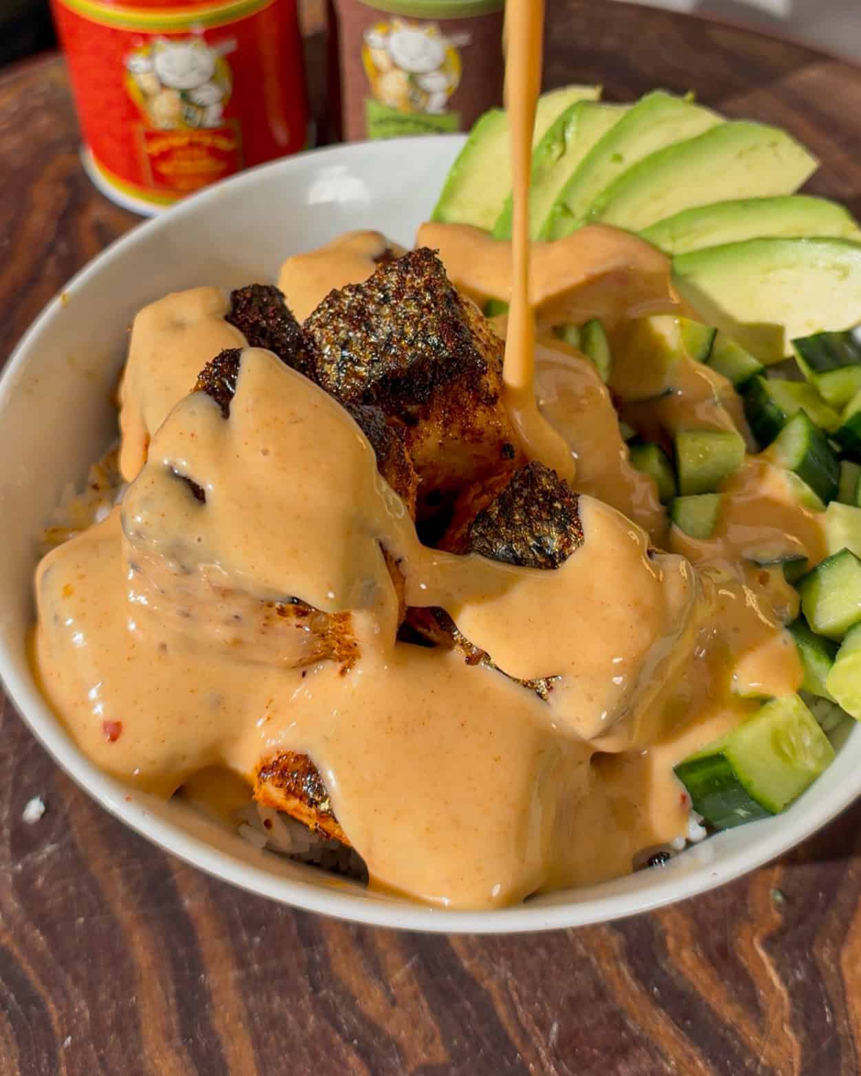 Juicy grilled chicken topped with creamy sauce, served with fresh avocado and cucumber slices.
