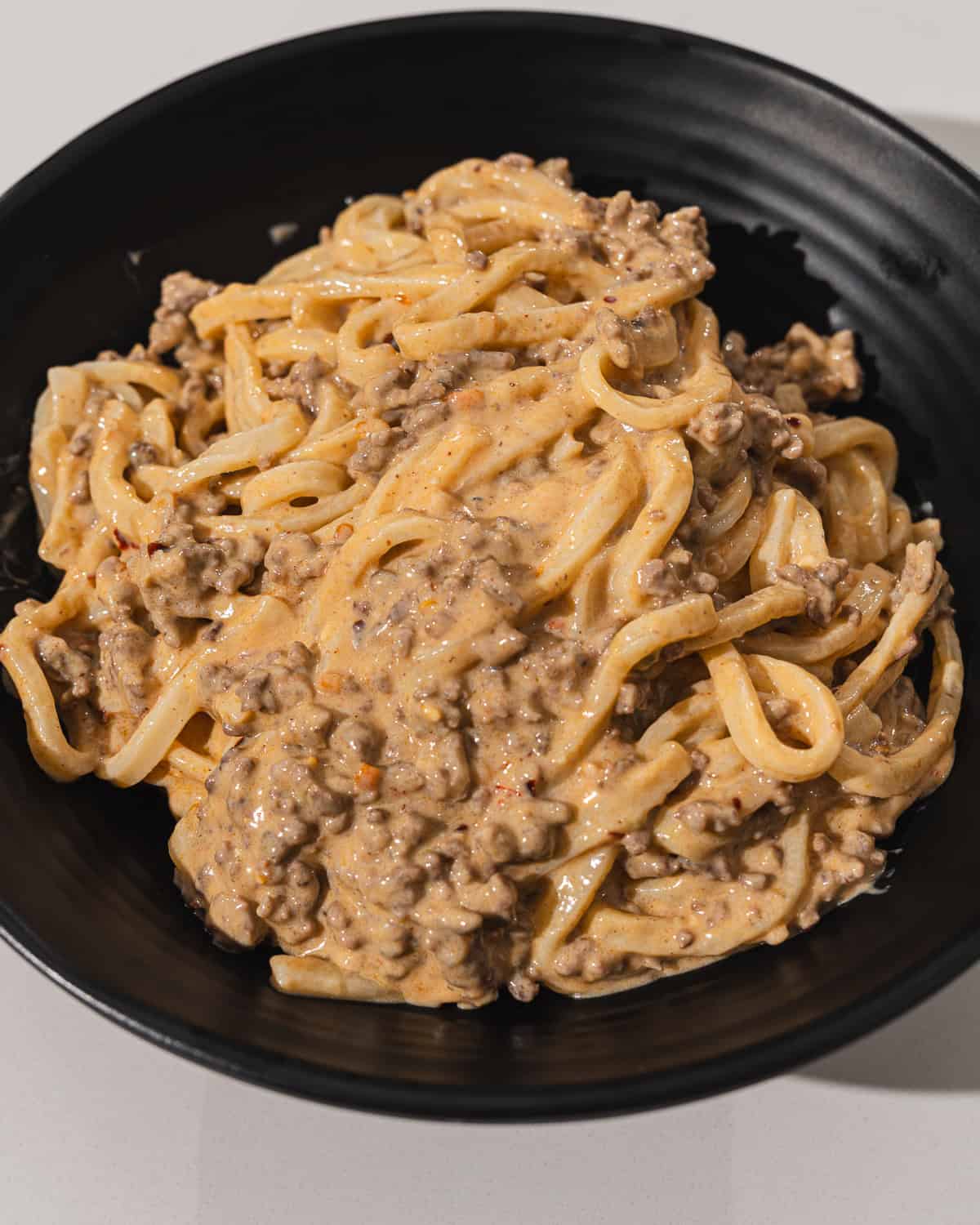 Creamy beef stroganoff with noodles in a black bowl, delicious comfort food.