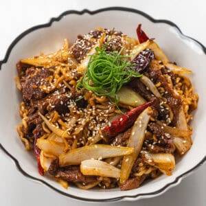 Delicious beef stir-fry with vegetables, noodles, and sesame seeds, perfect for a quick and flavorfu.