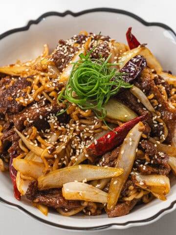 Delicious beef stir-fry with vegetables, noodles, and sesame seeds, perfect for a quick and flavorfu.