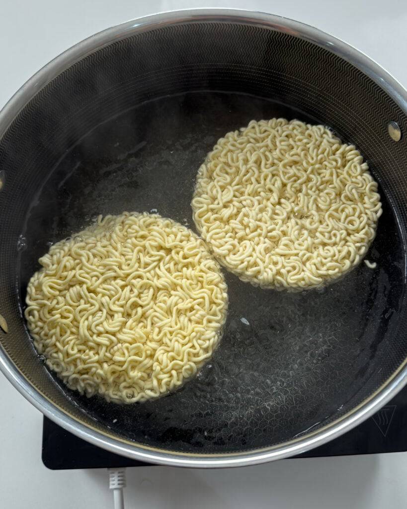 Ramen noodles submerged in liquid during Mongolian Beef Noodles preparation