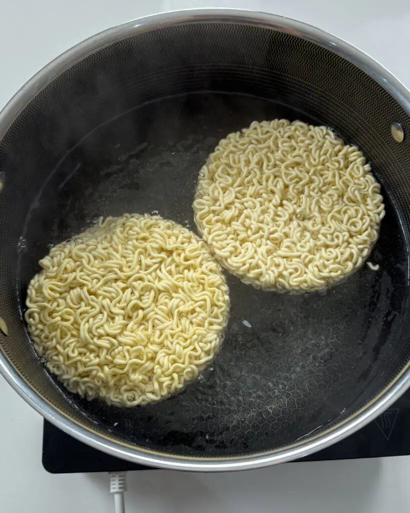 Ramen noodles submerged in liquid during Mongolian Beef Noodles preparation - GENIUS EATS Ramen noodles submerged in liquid during Mongolian Beef Noodles preparation