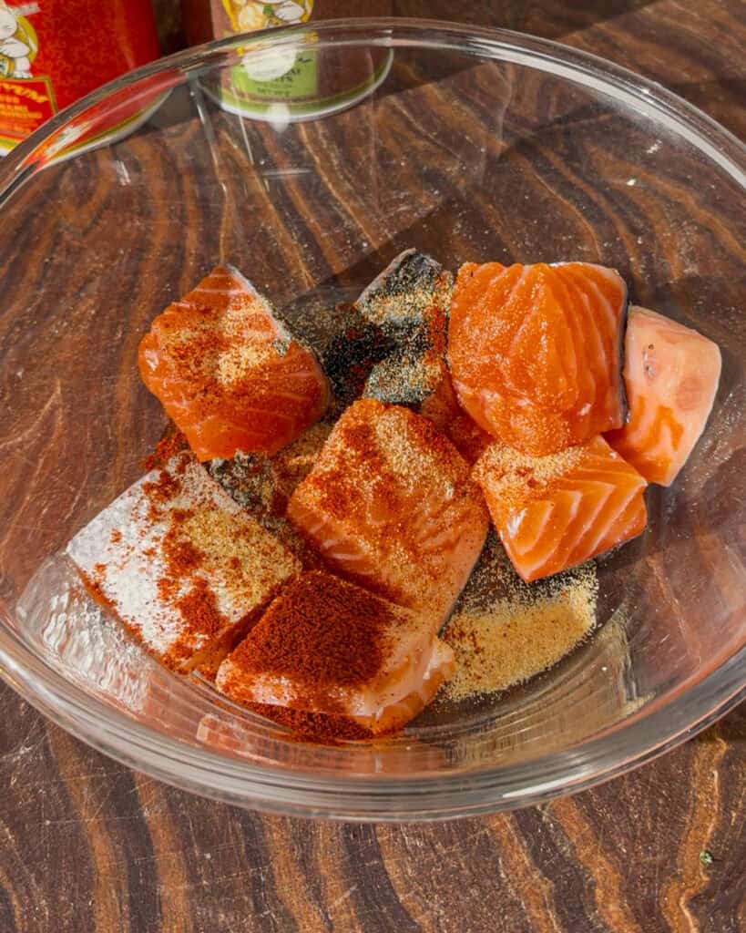 Raw salmon cubes with skin placed in a glass bowl