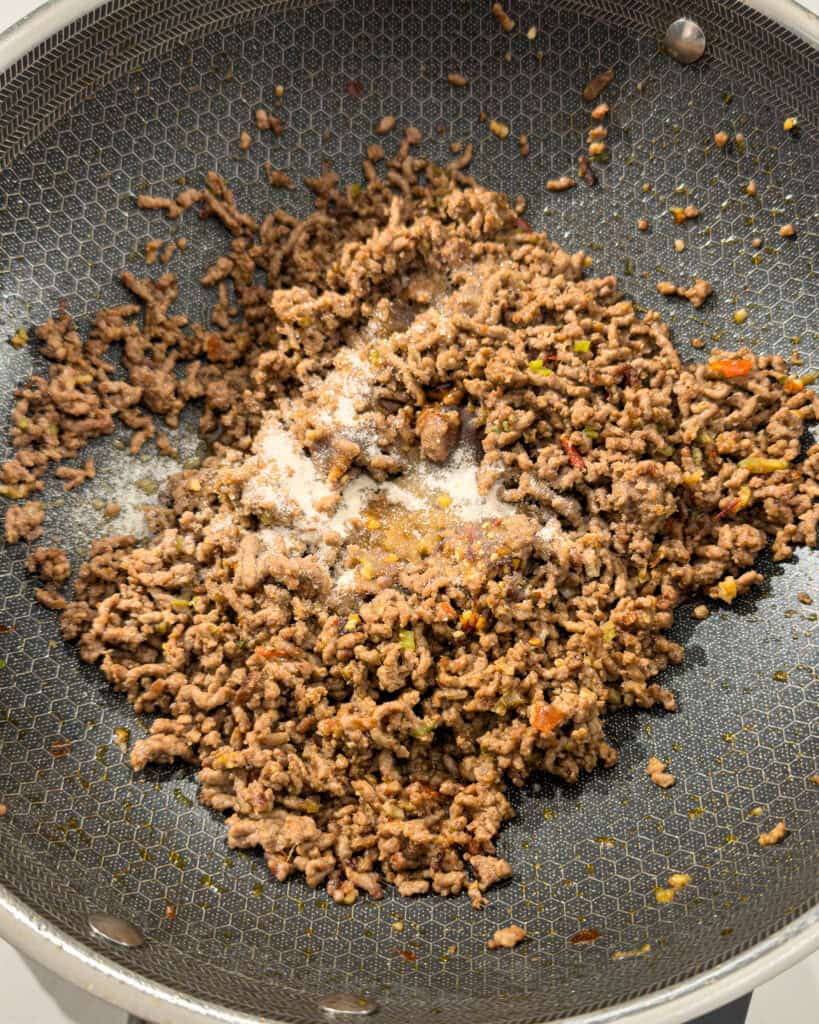 Seasoning added to cooked minced pork in pan