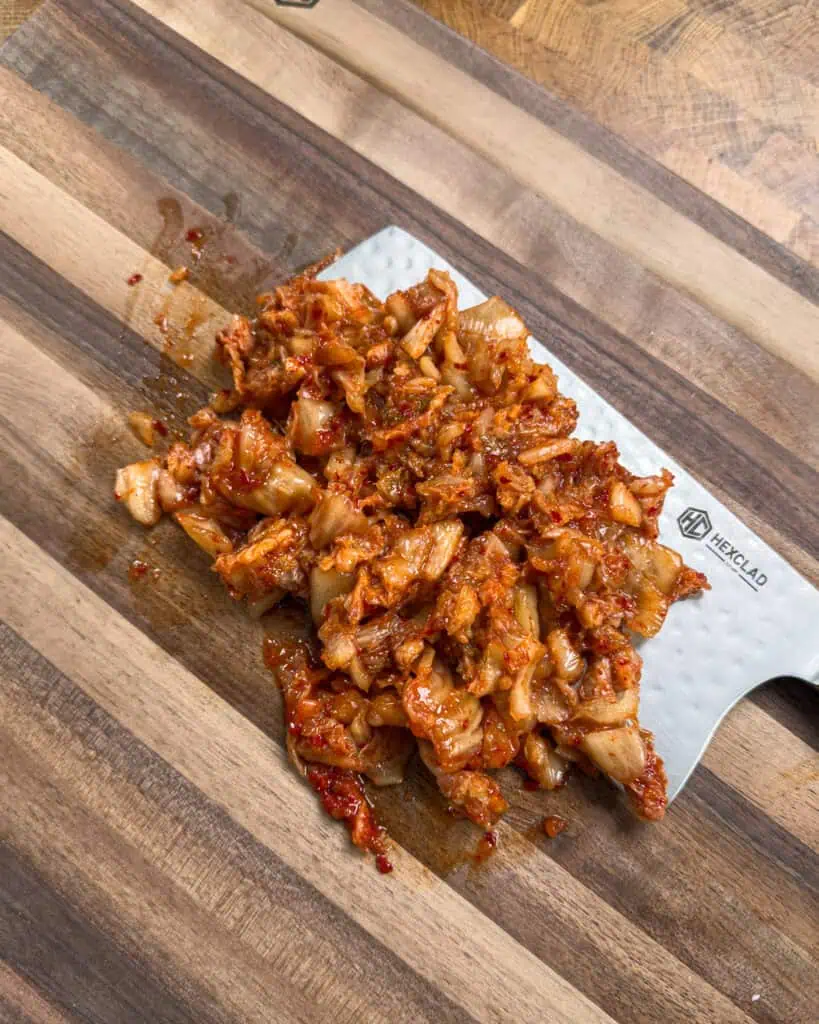 Genius Eats Spicy Pork Stir-Fry. - GENIUS EATS Sliced raw bacon arranged on a wooden cutting board for Kimchi Bacon Pasta preparation
