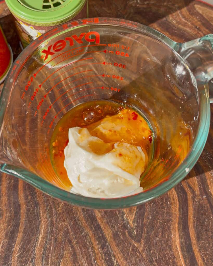 White and orange sauce ingredients combined in a measuring cup