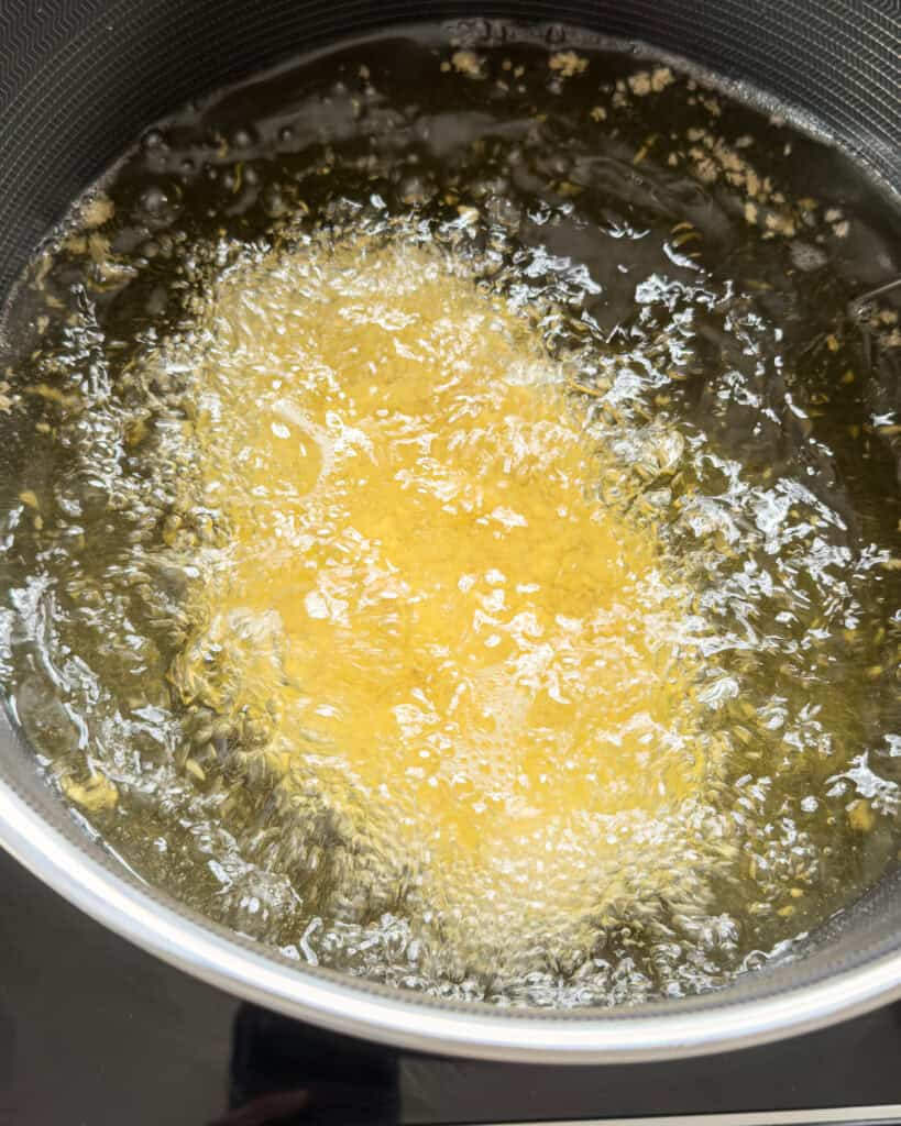 Breaded chicken held over hot oil before frying