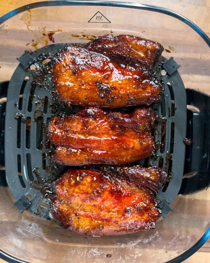Cooked pork belly pieces inside air fryer basket - GENIUS EATS Cooked pork belly pieces inside air fryer basket