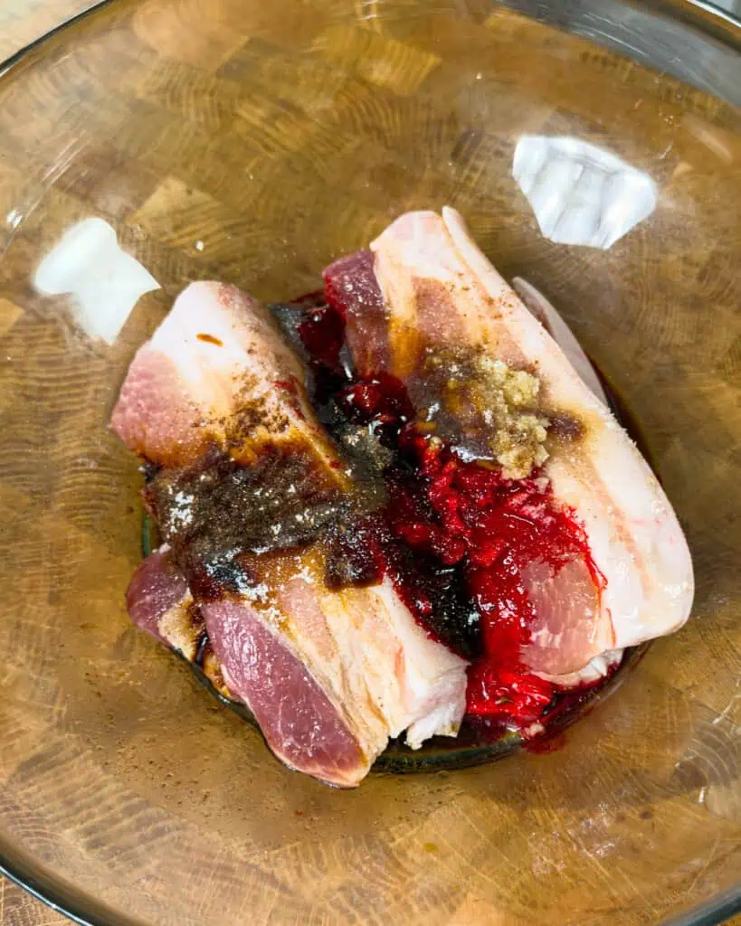 Pork belly soaking in marinade inside a glass bowl for Char Siu Pork Belly - GENIUS EATS Pork belly soaking in marinade inside a glass bowl for Char Siu Pork Belly