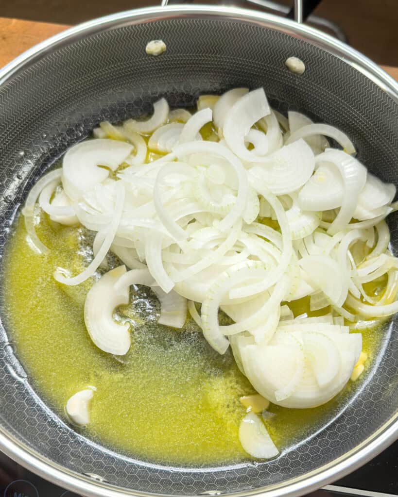 Sliced onions cooking in melted butter in a pan