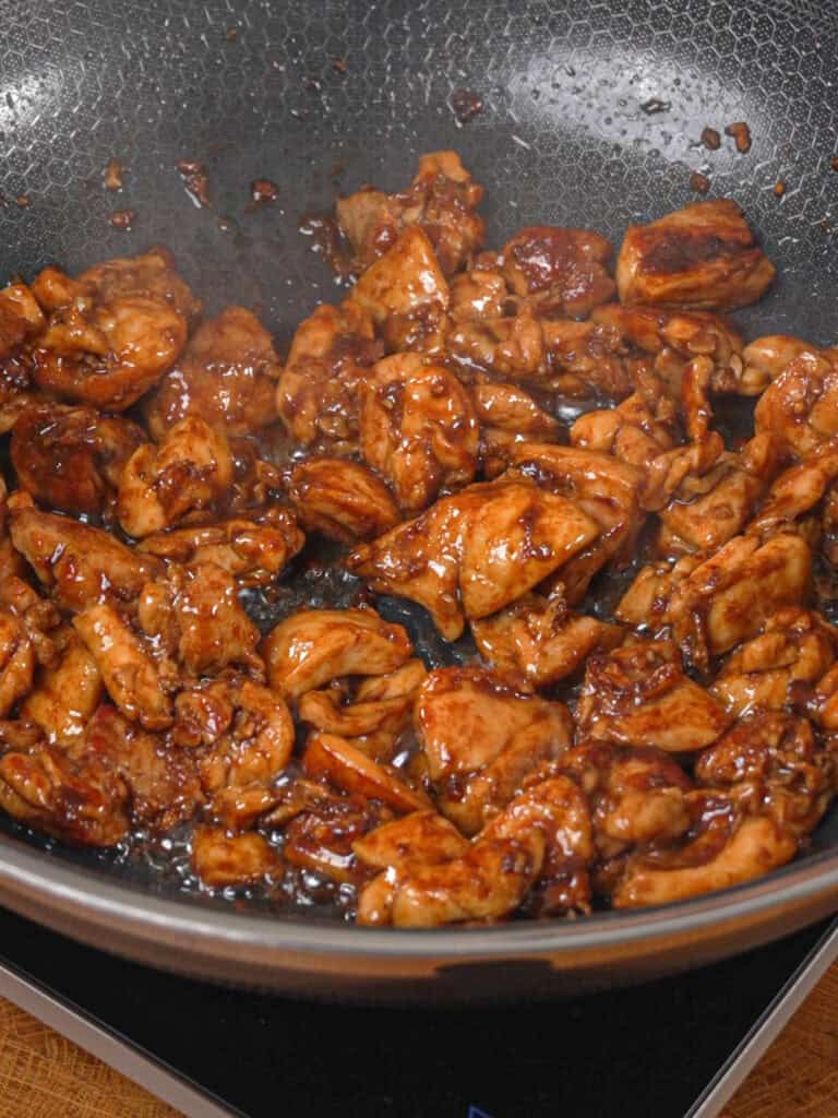 Chicken pieces browning and cooking in sauce for General Tso-Style Chicken Chow Mein.