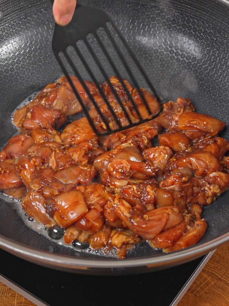 Marinated chicken stir-frying in a wok for General Tso-Style Chicken Chow Mein.