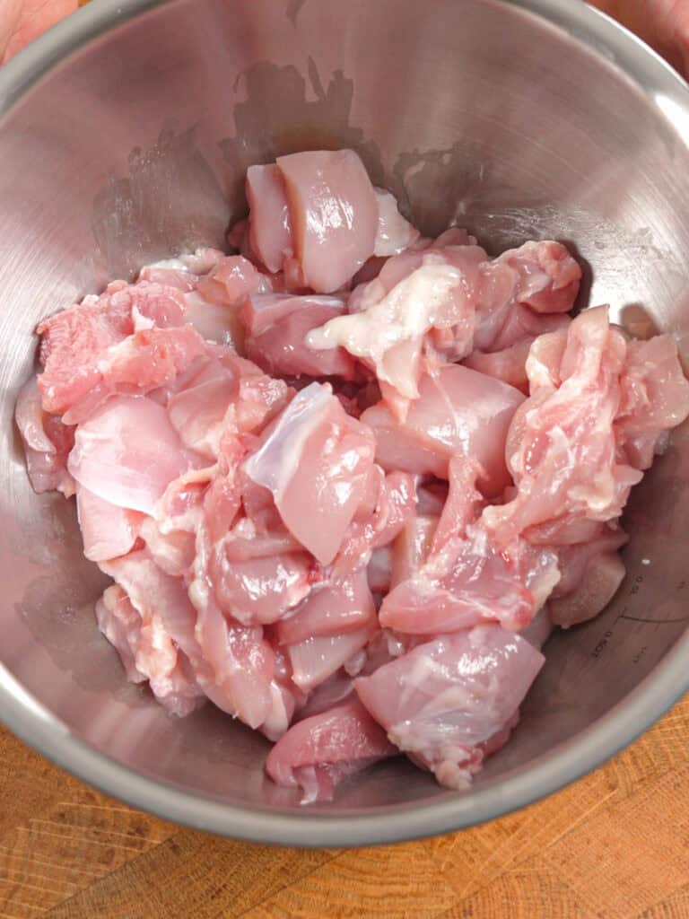 Raw sliced chicken thighs in a mixing bowl prepared for marinating for General Tso-Style Chicken Chow Mein