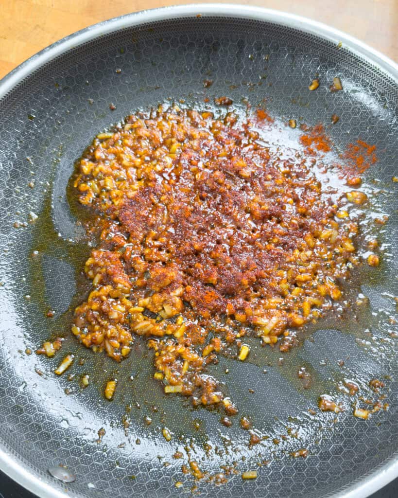 Chopped browned pieces cooking in oil in a pan
