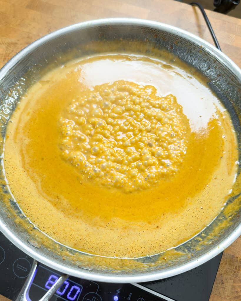 Orange sauce bubbling in a pan
