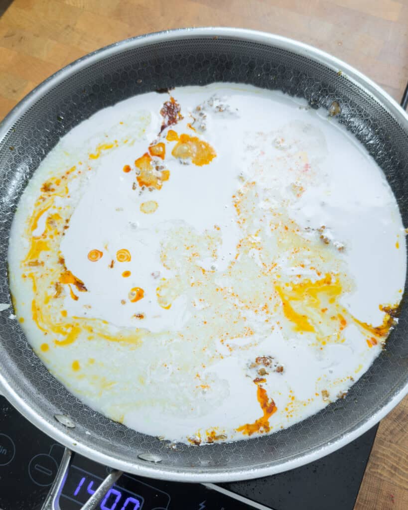 Small browned bits visible in a pan with white liquid and orange oil patches
