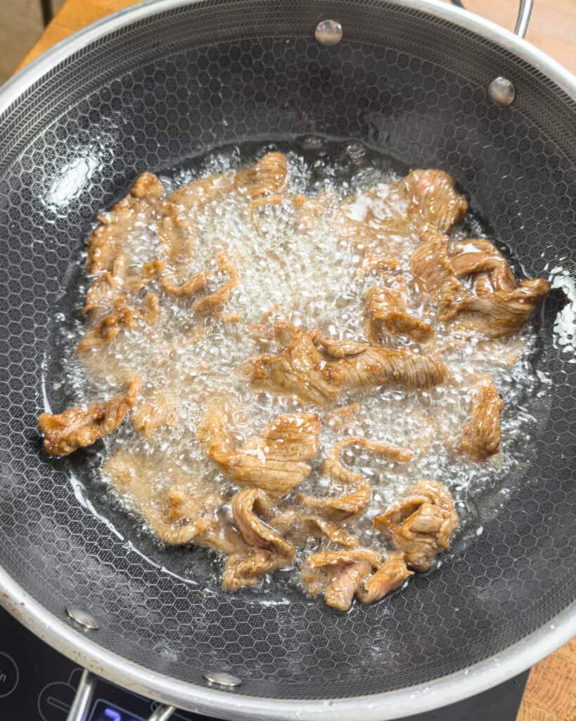 Beef pieces cooking in bubbling oil - GENIUS EATS Beef pieces cooking in bubbling oil