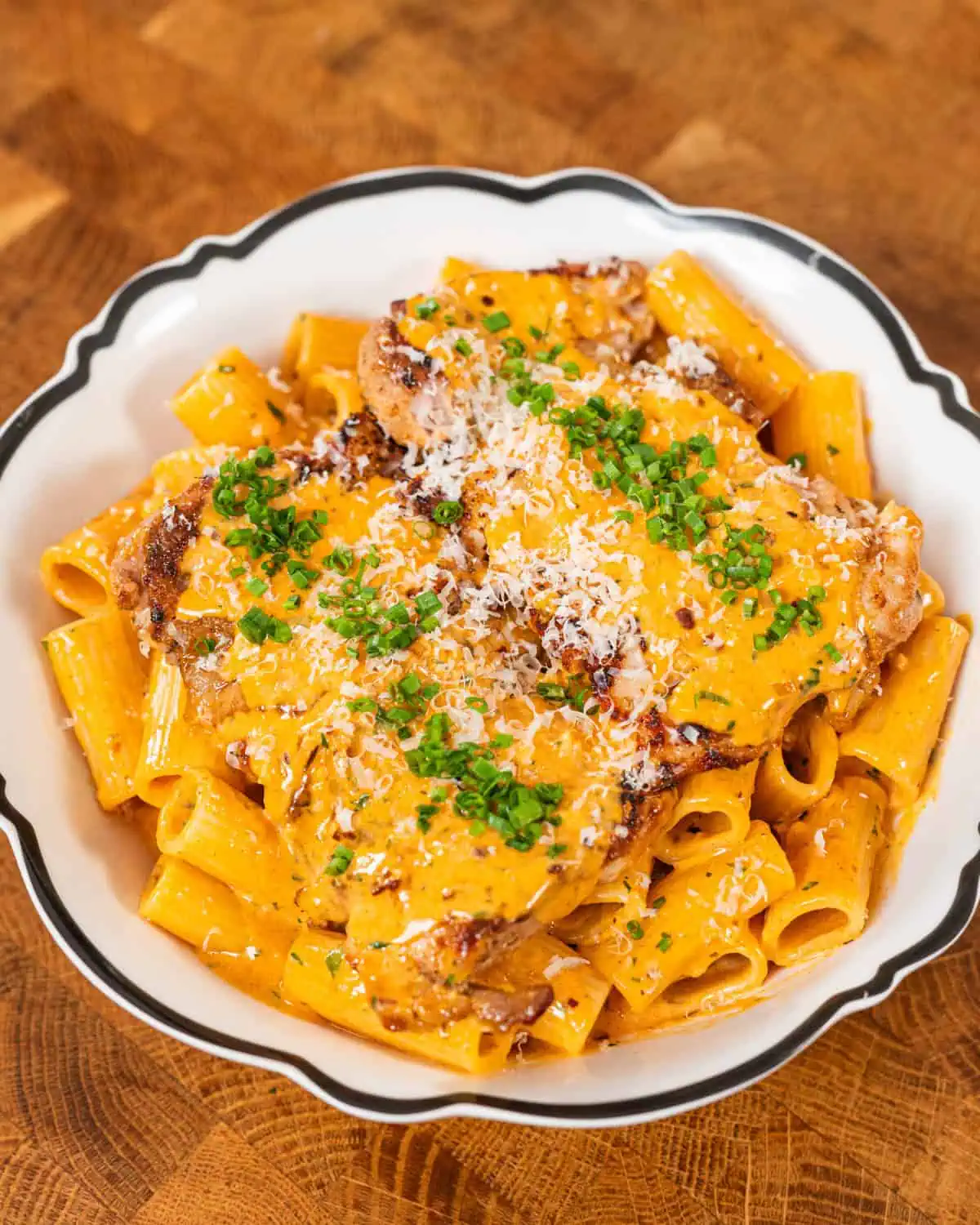 Close up of gochujang chicken alfredo pasta with chilli flakes - GENIUS EATS Bowl of creamy gochujang chicken alfredo pasta with chilli flakes