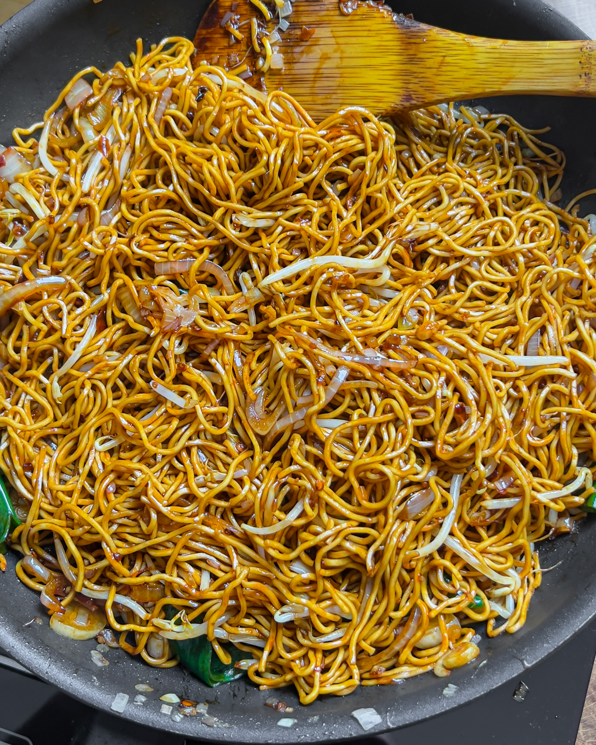Tossing the noodles until fully coated in dark glossy sauce for Chili Oil Soy Sauce Chow Mein - GENIUS EATS Tossing the noodles until fully coated in dark glossy sauce for Chili Oil Soy Sauce Chow Mein