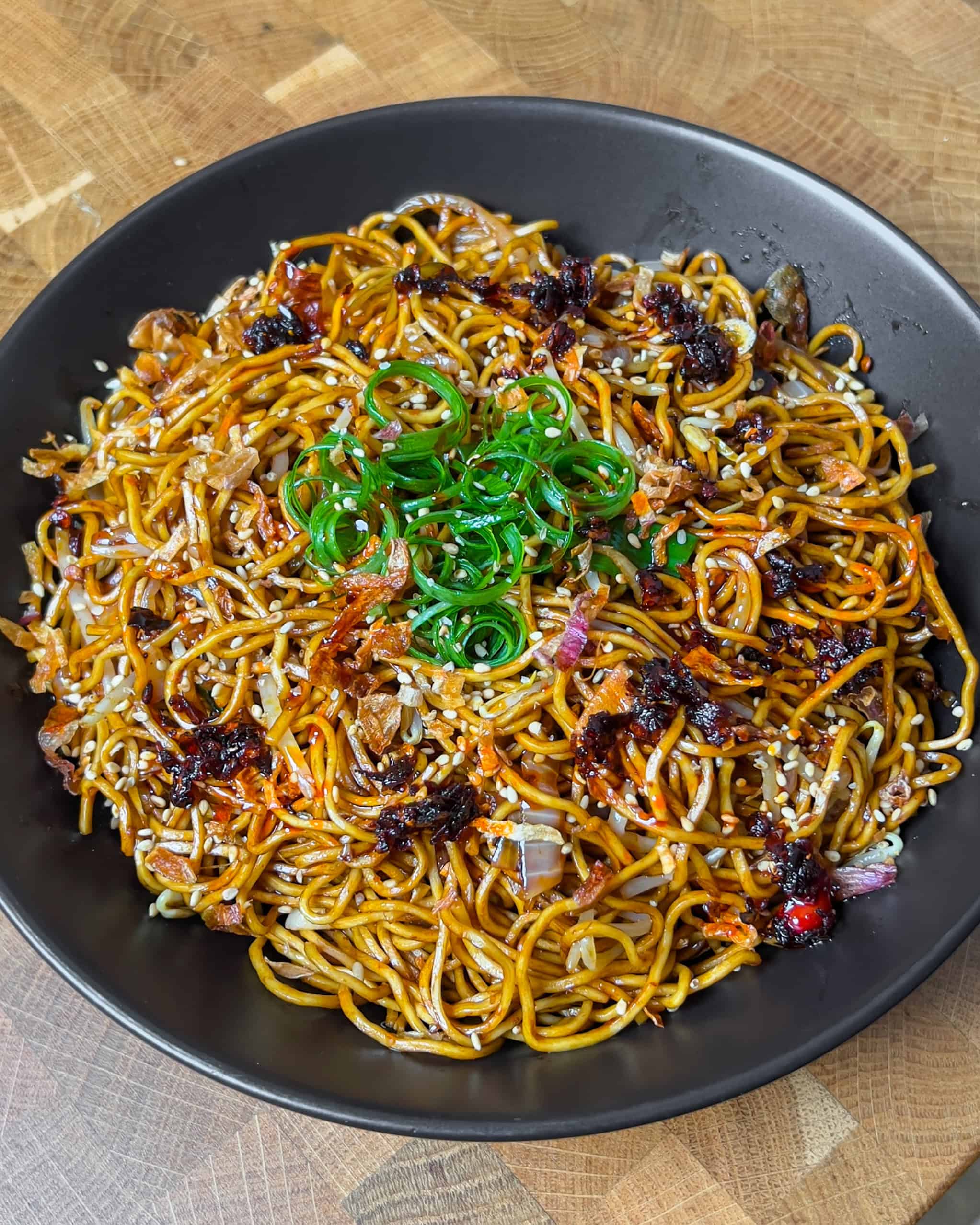 Finished Chili Oil Soy Sauce Chow Mein garnished with green onions in the pan - GENIUS EATS Finished Chili Oil Soy Sauce Chow Mein garnished with green onions in the pan